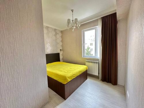 a bedroom with a yellow bed and a window at Graz Narek house 3 in Altenfelden