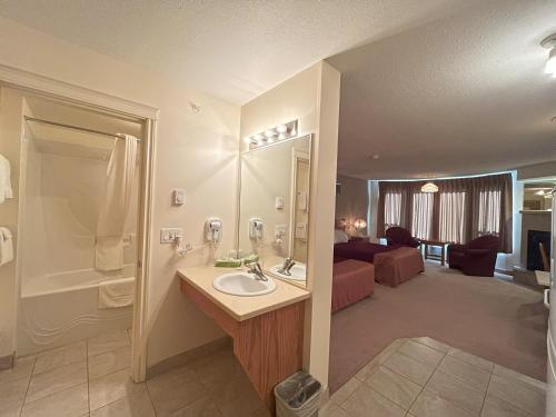 a bathroom with a sink and a shower and a bedroom at Western Budget Motel Ponoka in Ponoka
