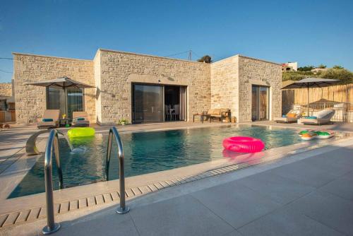 a swimming pool with two frisbees in front of a house at Villa Stone Diamond in Sívas