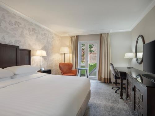 a hotel room with a bed and a desk and a window at Delta Hotels by Marriott Tudor Park Country Club in Maidstone