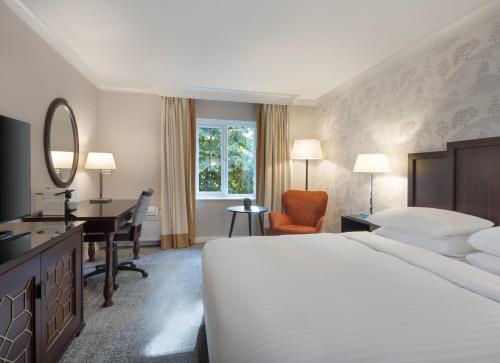 a hotel room with a large bed and a desk at Delta Hotels by Marriott Tudor Park Country Club in Maidstone