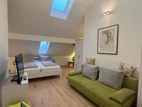 Gaestehaus Seliger في ميرسبرغ: غرفة معيشة بها أريكة خضراء وتلفزيون