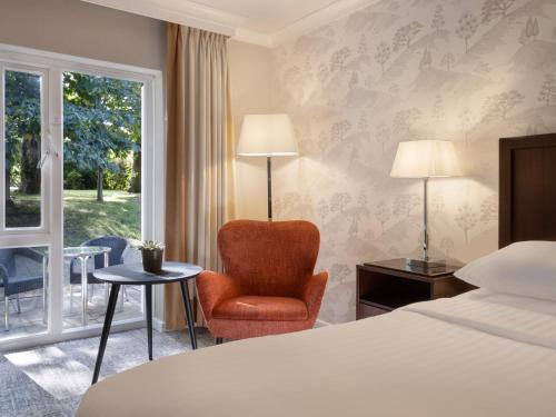 Pokój hotelowy z łóżkiem, krzesłem i oknem w obiekcie Delta Hotels by Marriott Tudor Park Country Club w mieście Maidstone