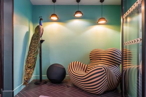a room with a chair and a peacock statue at Hotel Archetype Etoile in Paris