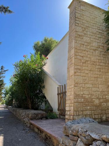 a brick building with a gate and a stone wall at Casette Masseria La Camardia in Sava