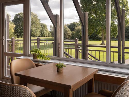 a table and chairs in a room with windows at Delta Hotels by Marriott Tudor Park Country Club in Maidstone