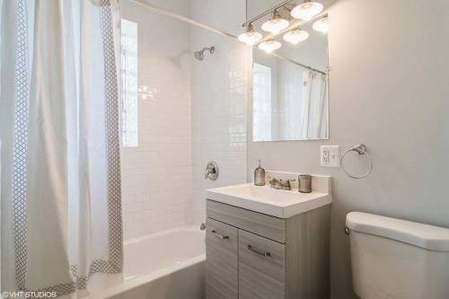 baño blanco con lavabo, bañera y aseo en 2 Bed l 5 min from Med District l Free Parking, en Chicago