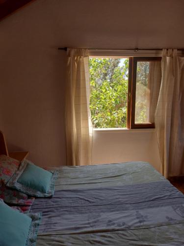 a bedroom with a bed in front of a window at Pa-kuas del Uritorco in Capilla del Monte