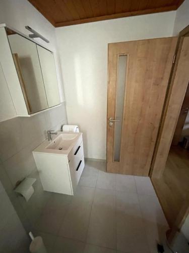 a bathroom with a sink and a wooden door at Pension Balm in Meiringen