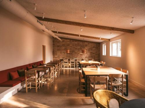 a dining room with tables and chairs and a brick wall at wecamp Cadaqués in Cadaqués