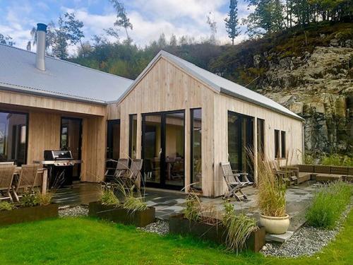 a wooden house with chairs and a table in a yard at Hytte til leie i Ryfylke in Hjelmeland