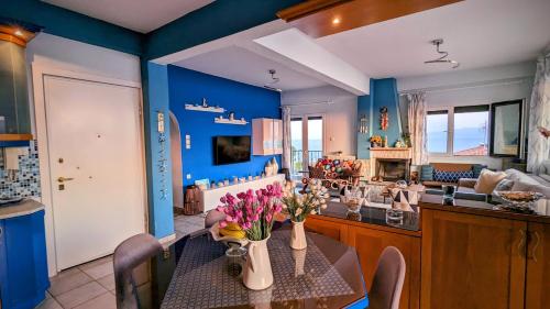 un comedor con paredes azules y una mesa con flores. en Bellevue - Panoramic Seaview Penthouse, en Pyrgadikia