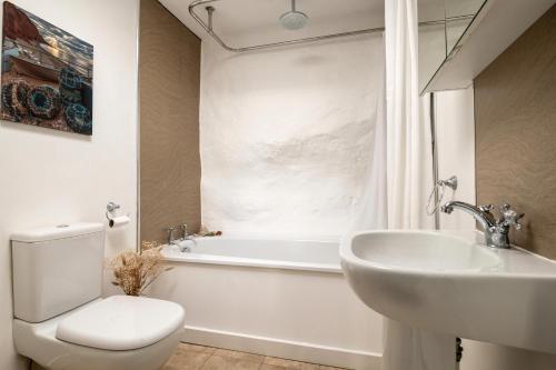 a bathroom with a toilet and a sink and a tub at Bulverton House Holiday Cottages in Sidmouth