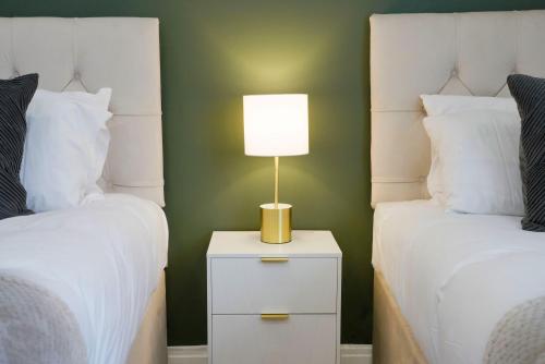 a bedroom with two beds and a lamp on a night stand at Central Buckingham Apartment #9 with Free Parking, Pool Table, Fast Wifi and Smart TV with Netflix by Yoko Property in Buckingham