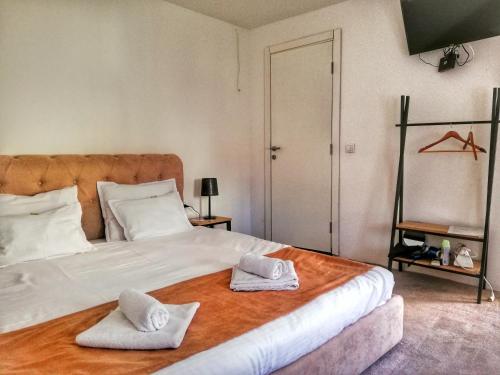 - une chambre avec un grand lit et des serviettes dans l'établissement OnLux sobe, à Kragujevac