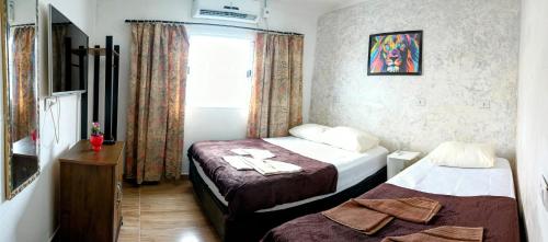 um quarto de hotel com duas camas e uma janela em Casa da Lú - Praia e Piscina na Praia Grande