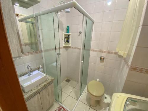 a bathroom with a shower and a toilet and a sink at Apartamento de frente com sacada no centro de Capão da Canoa in Capão da Canoa