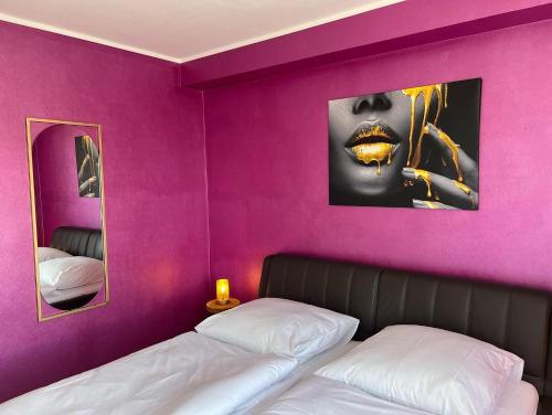 a bedroom with a purple wall with a bed and a mirror at Apartment Am Paradies in Bad Lauterberg