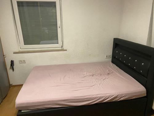 a bed with a pink mattress in a room with a window at vasu Muthalagan in Aalen