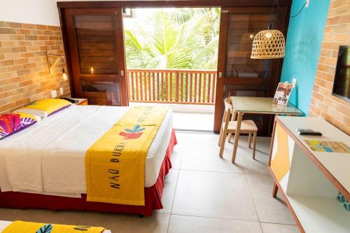 a bedroom with a bed and a table and a balcony at Hotel Village Porto De Galinhas in Porto De Galinhas