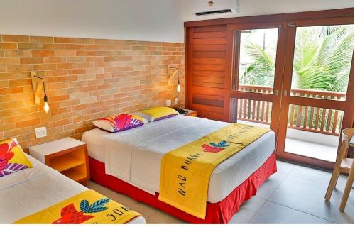 two beds in a room with a brick wall at Hotel Village Porto De Galinhas in Porto De Galinhas