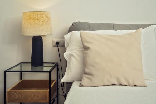 a bed with a side table with a pillow and a lamp at infinity Castellabate b & b di Charme in Santa Maria di Castellabate