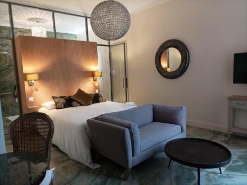 a bedroom with a bed and a couch and a mirror at LA MAISON DU SOLEIL in LʼIsle-Jourdain
