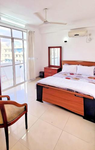 ein Schlafzimmer mit einem großen Bett und einem Stuhl in der Unterkunft Beach Road holiday home in Karagampitiya