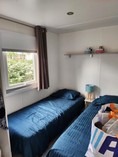 a bedroom with two beds and a window at camping sable du midi 4 etoile in Valras-Plage