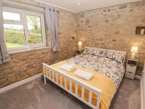 a bedroom with a bed and a stone wall at The Stable in Narberth