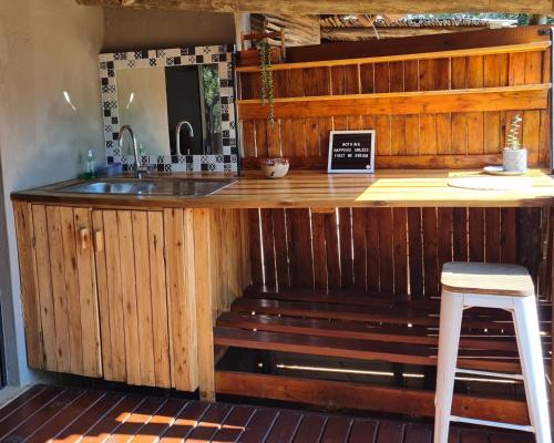 a kitchen with a counter with a sink and a stool at The Dreamcatcher Lodge in Hoedspruit