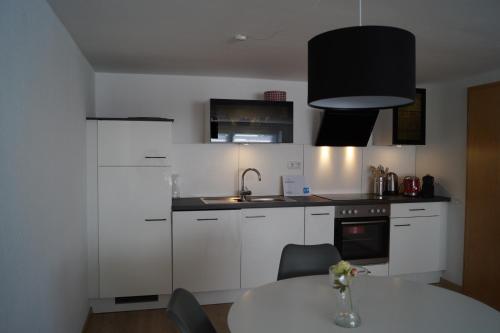 a kitchen with white cabinets and a white table at Astentraum in Winterberg
