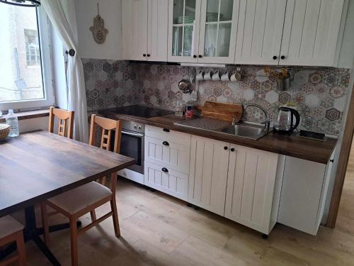 uma cozinha com armários brancos, uma mesa e um lavatório em Chata u Vajdov em Stará Lehota