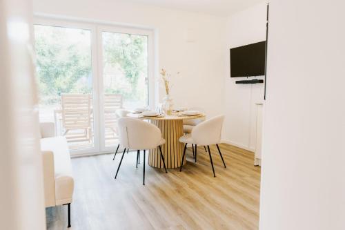 - une salle à manger avec une table, des chaises et une télévision dans l'établissement Küsten Suite de See - Suite 1 direkte Deichlage, Terrasse, 53qm, à Greetsiel