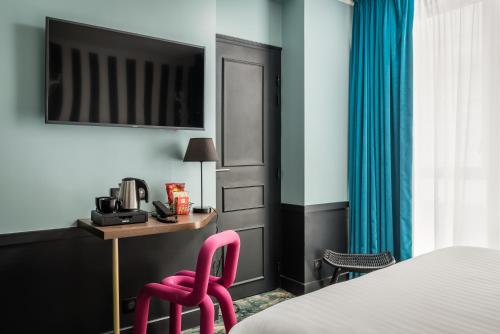 a hotel room with a bed and a desk and a pink chair at Hotel Archetype Etoile in Paris