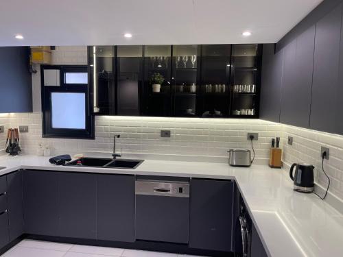 a kitchen with black cabinets and a sink at Family sumptuous apartment At Melsa - Nasr City. in Cairo