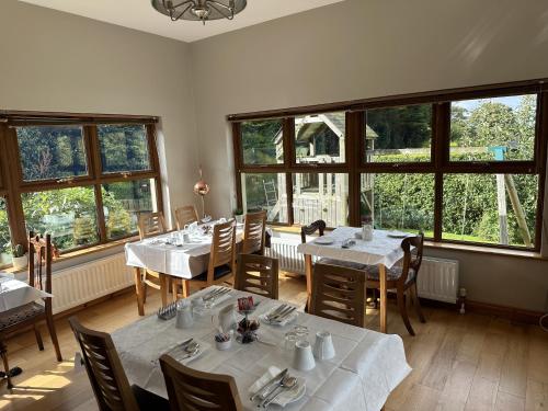 a dining room with tables and chairs and windows at Dunhill Cottage B&B in Hillsborough