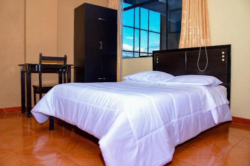 a bedroom with a large white bed with a window at Hotel Santa Ana in Ayacucho