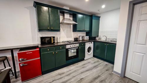 a kitchen with green cabinets and a washing machine at Modern City Centre Apartment in Belfast