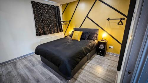 a bedroom with a black bed with a yellow wall at Modern City Centre Apartment in Belfast