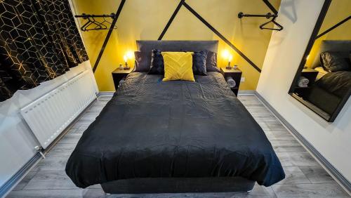 a large black bed in a room with yellow pillows at Modern City Centre Apartment in Belfast