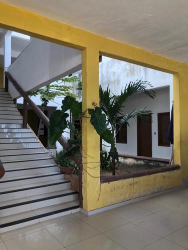 un bâtiment avec un pilier jaune et des escaliers en avant dans l'établissement Pousada leblon, à Caucaia