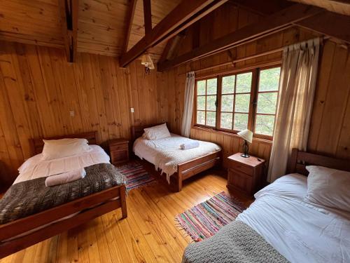 a bedroom with two beds in a wooden cabin at Green Baker Lodge in Puerto Bertrand