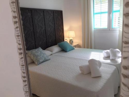 una camera da letto con un grande letto bianco con asciugamani di Apartamentos Roca Plana - Formentera Break a Es Pujols