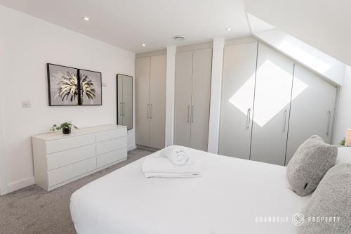 a white bedroom with a large white bed and cabinets at Carbery Ridge by Grandeur Property in Bournemouth