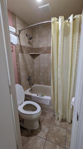 a bathroom with a toilet and a tub with a shower curtain at Portland Value Inn in Portland