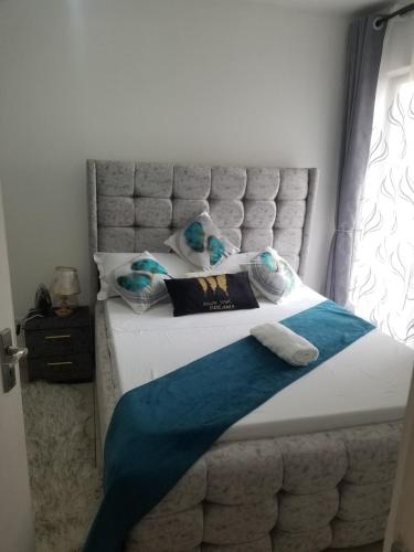 a bed with a white and blue blanket on it at Pangani Oasis Gem 2-BR Stylish Apartment in Nairobi