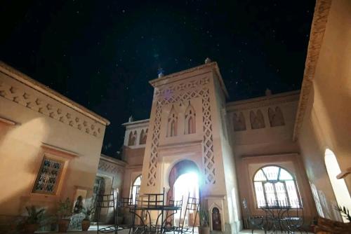 a large building with a clock tower at night at Kasbah Ait Kassi in Boumalne