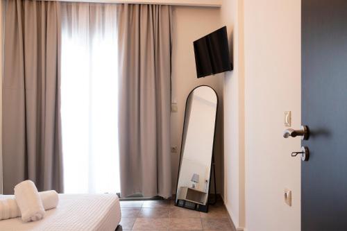 a bedroom with a bed and a mirror and a television at Olymp-rooms in Litochoro