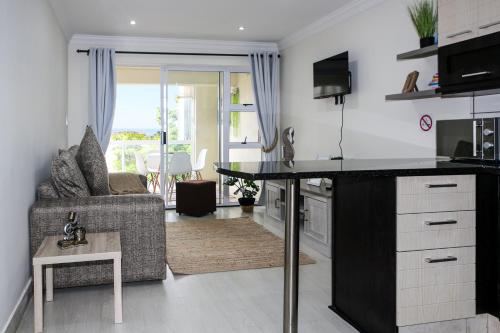 a kitchen and living room with a table and a couch at Shell Shores -Apartment with balcony, Sea views and private parking in Jeffreys Bay
